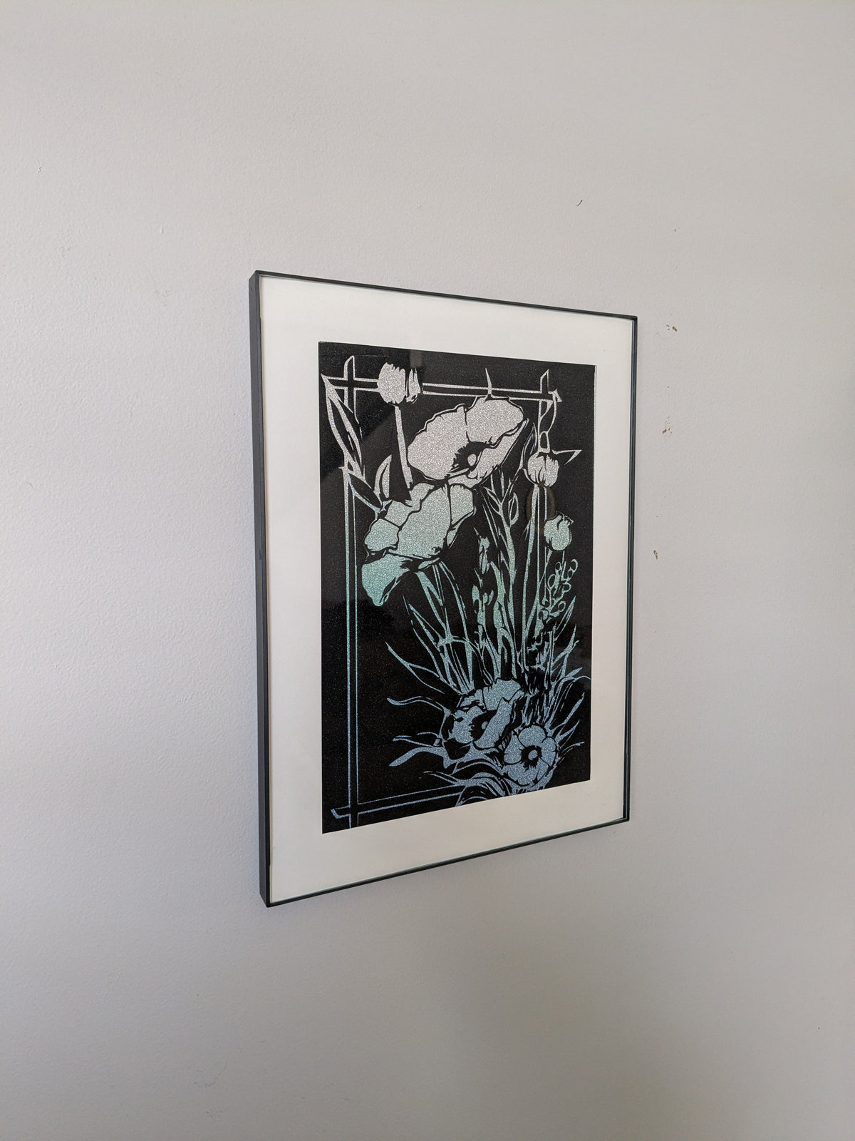 Teal and white botanical line art of poppies and wildflowers on black background in black frame with white mat