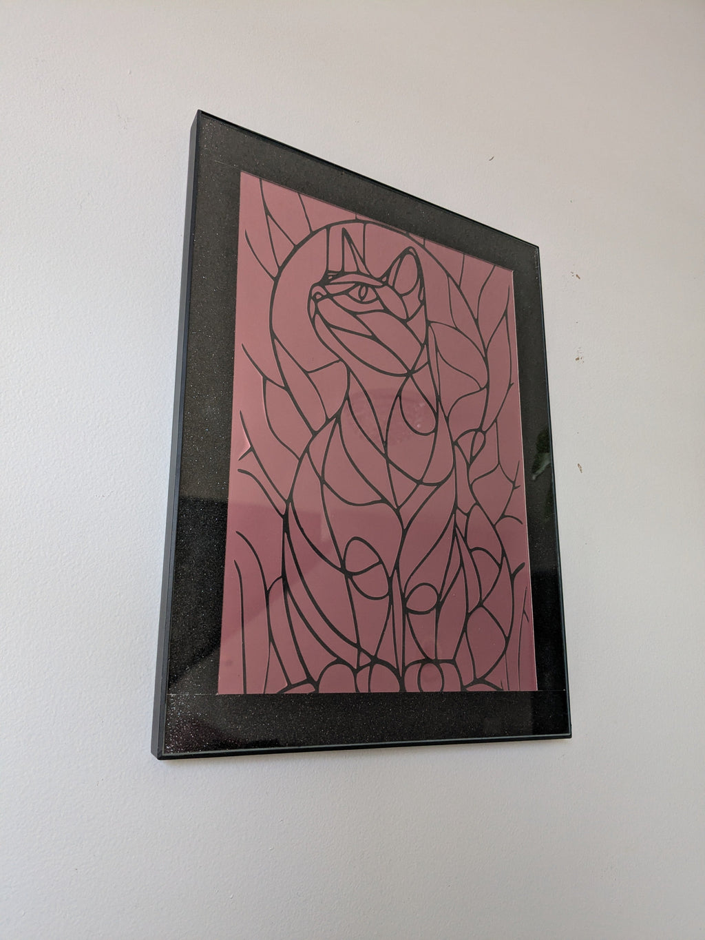 Black line art cat surrounded by organic leaf shapes on dusty rose pink background in black frame