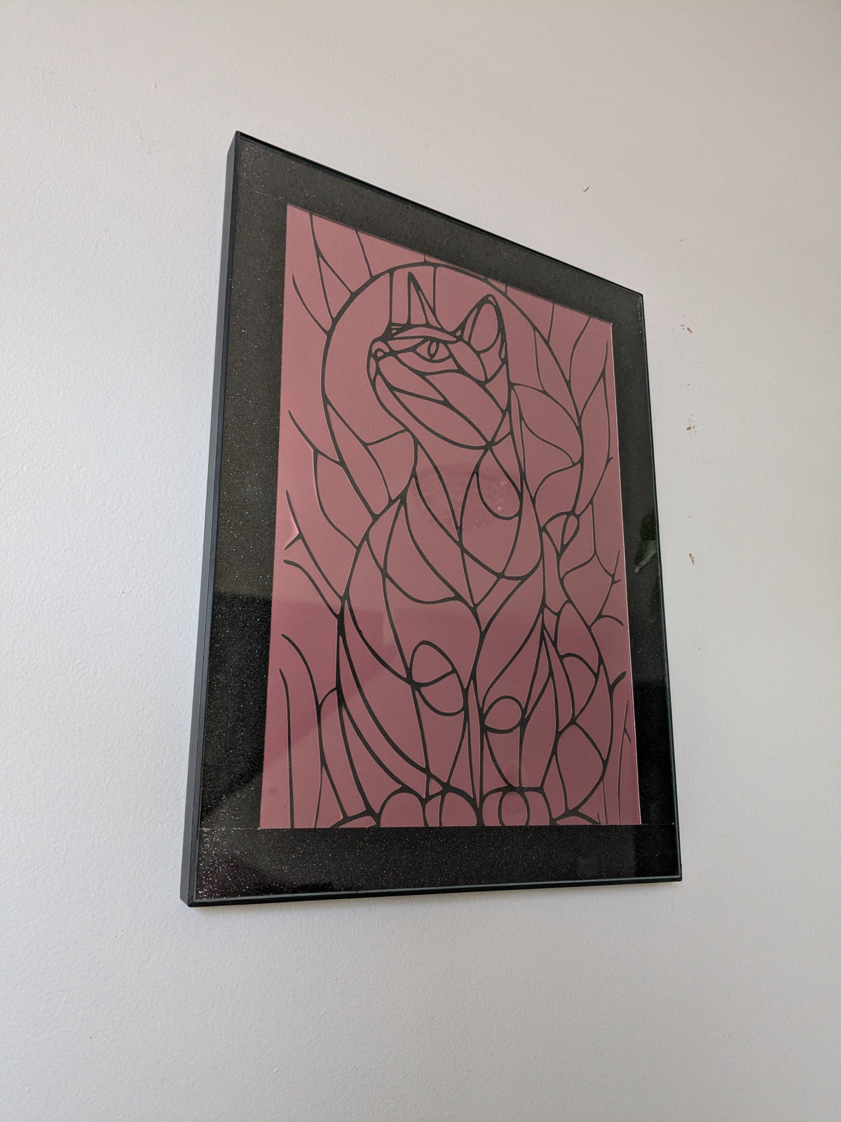 Black line art cat surrounded by organic leaf shapes on dusty rose pink background in black frame