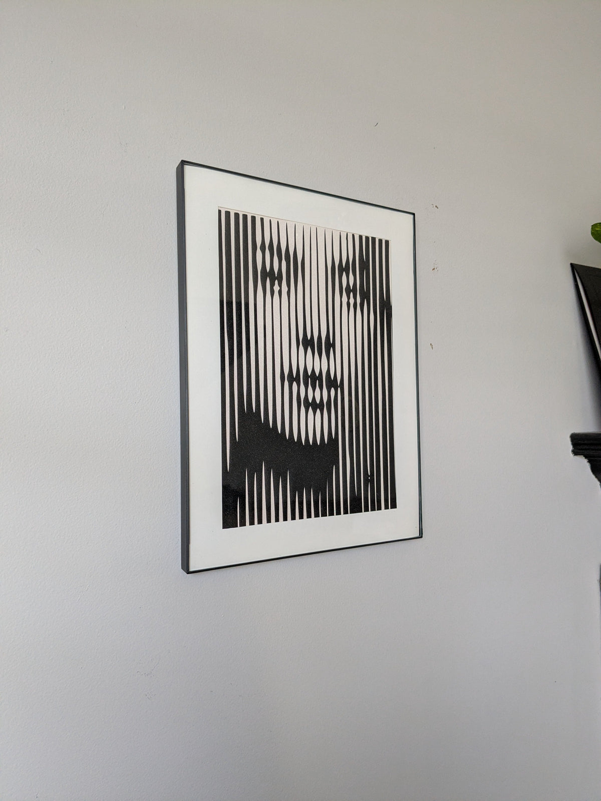 Black and white op art portrait made of vertical lines forming a face, black frame with white mat